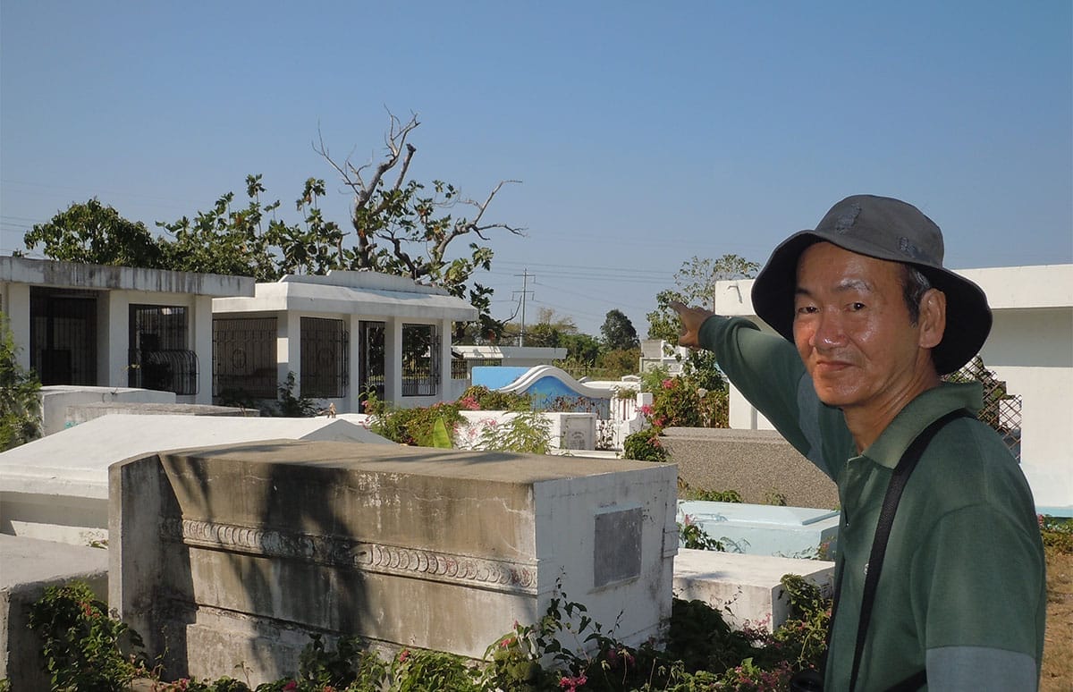 Richard Ruiz points to the tree where he saw the White-Cheeked (Gray) Starling at the Chinese cemetery. 